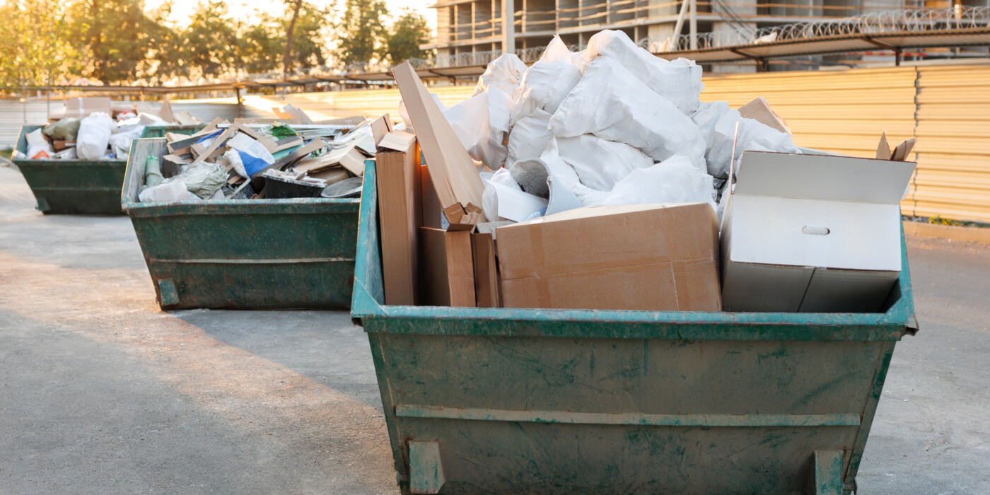 bennes de chantier contenant des déchets , devant un immeuble en construction.
