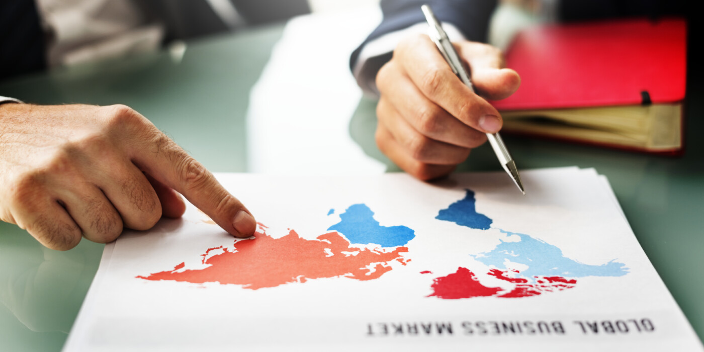 2 Professionnels réunis autour d'une carte du monde sur laquelle est écrit : Global Business Market