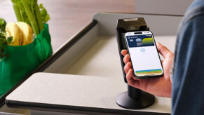 Main tenant un portable au-dessus d'un lecteur de cartes à une caisse de supermarché