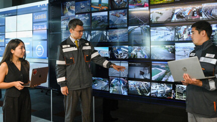 3 personnes regardent un mur rempli d'écrans