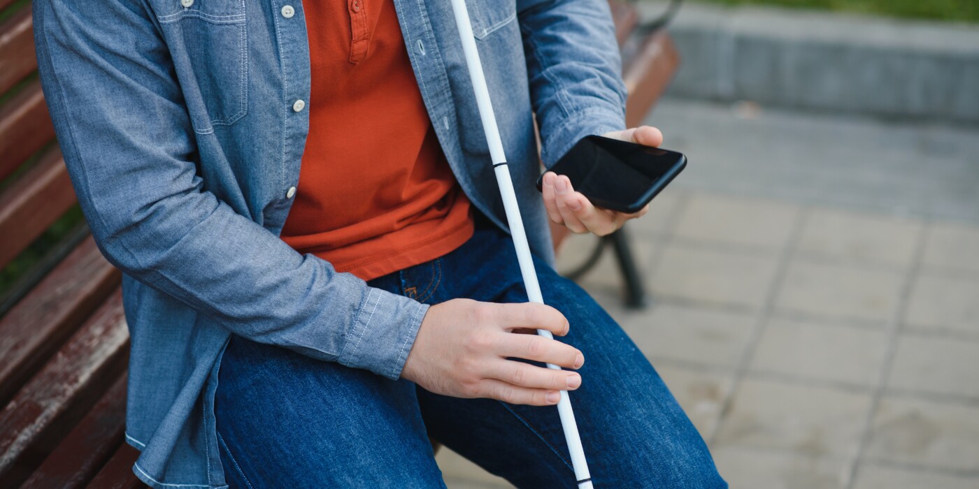 Young blinded man using phone and sending voice message.