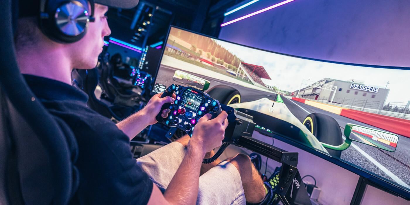 un jeune homme assis dans le siège d'un simulateur de pilotage automobile, au centre E-MOTION de GRIDX Luxembourg.