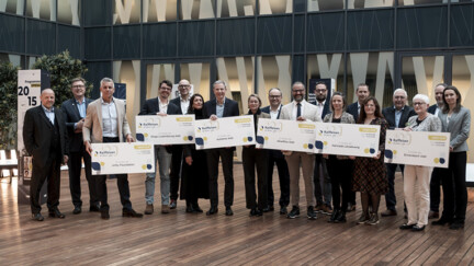 Plusieurs personnes sur une scène tenant ds chèques géants