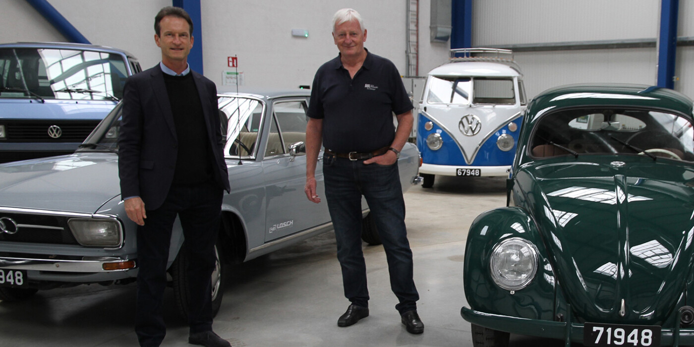 2 hommes au milieu de voitures dans un showroom