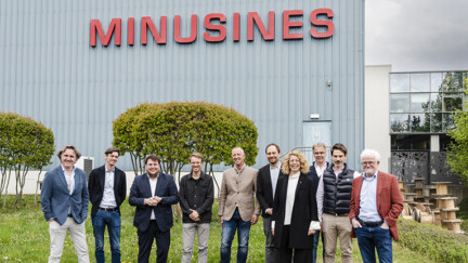 Plusieurs personnes devant un bâtiment industriel