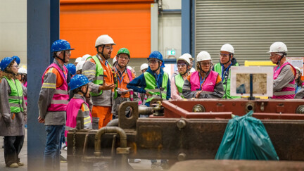 20e édition des Portes Ouvertes Luxembourg Plusieurs personnes avec casque et gilet de sécurité autour d'une machine