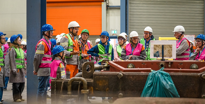 Plusieurs personnes avec casque et gilet de sécurité autour d'une machine