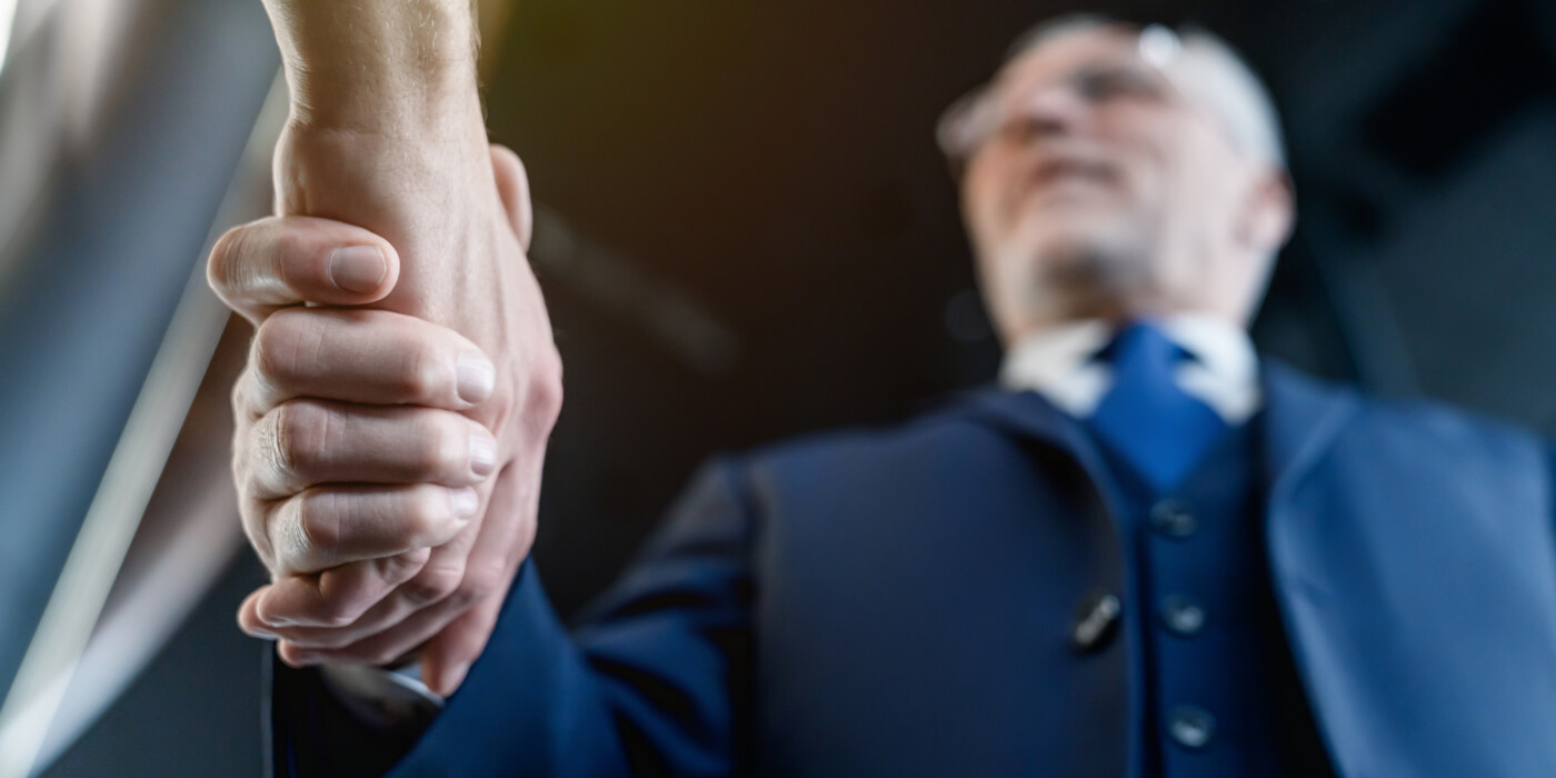 Une poignée de main avec un homme âgé en arrière-plan