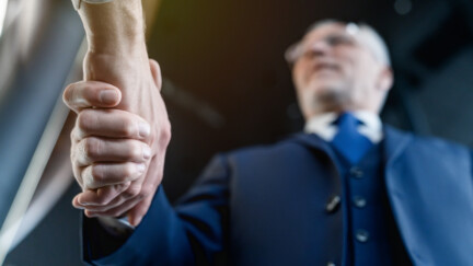 (Crédit : Envato) Une poignée de main avec un homme âgé en arrière-plan