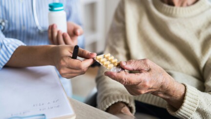 personnel soignant tendant une plaque de médicament à un patient âgé