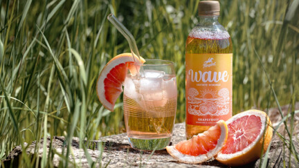 Bouteille, verre rempli et pamplemousse sur fond vegetal