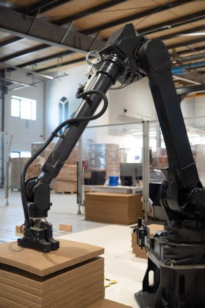 Un bras robotique manipule des plaques d'isolation biosourcées, à base de fibres végétales, qui sont directement intégrées au sein de la paroi porteuse en bois (crédit : Matthieu Freund Priacel / Primatt).