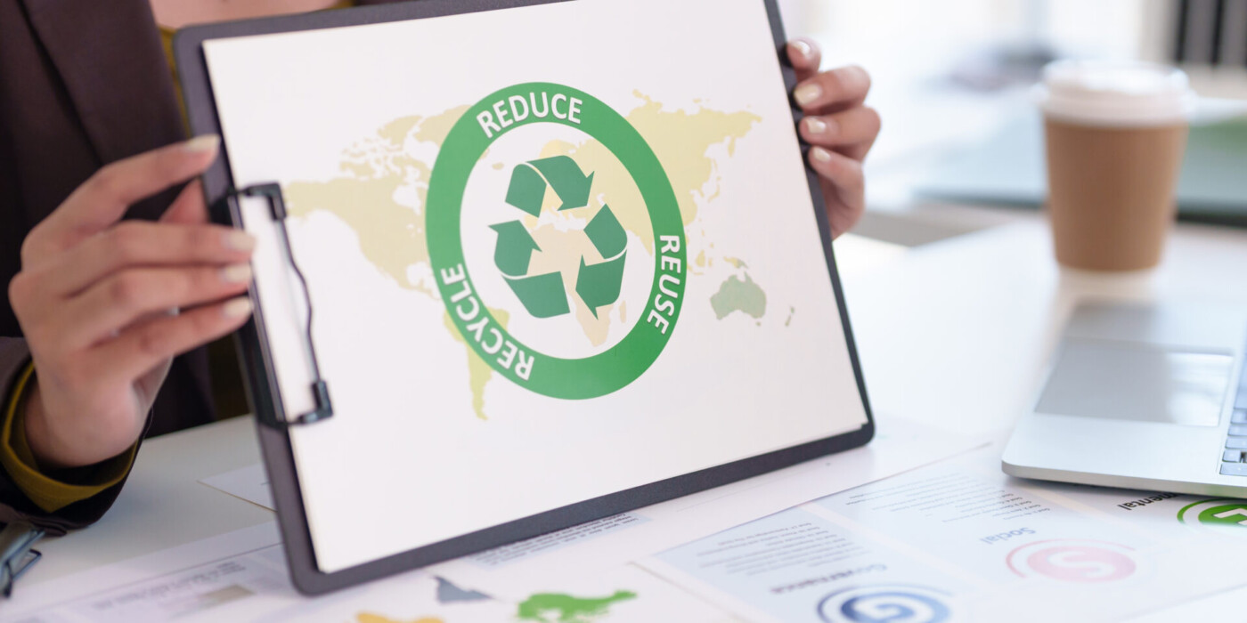 des mains de femmes tiennet un panneau où il est écrit : reduce,reuse, recycle,