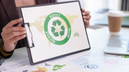 des mains de femmes tiennet un panneau où il est écrit : reduce,reuse, recycle,