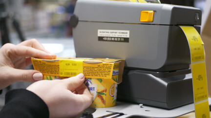 À l’occasion de ses 30 ans, Auchan Luxembourg célèbre plus d’1,2 million de produits sauvés du gaspillage alimentaire grâce aux solutions Smartway personne collant une étiquette sur un produit à côté d'une étiqueteuse