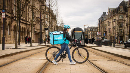Wolt partners with the European Transport Safety Council to help make city streets safer for couriers, cyclists and pedestrians Une personne traverse les rails du tram à côté d'un vélo